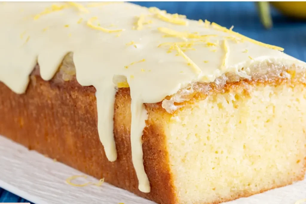 A beautifully decorated Lemon Cake with smooth cream cheese frosting, topped with lemon zest , sitting on a white plate.