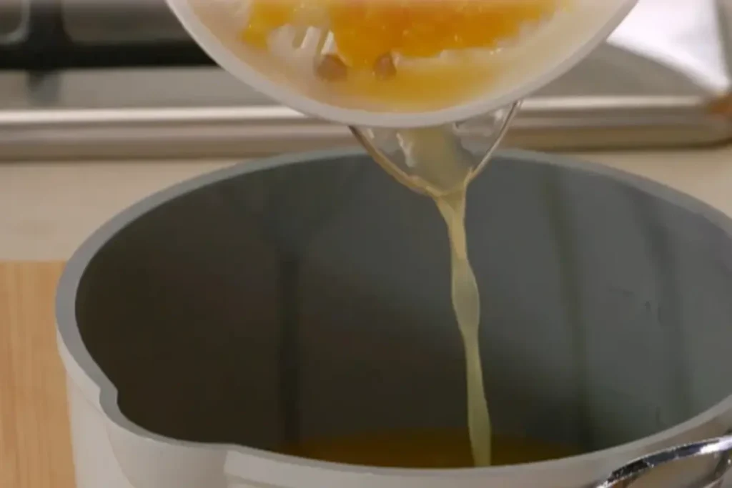 A close-up image of freshly squeezed lemon juice and sugar being mixed in a saucepan on a stove, creating a glossy syrup, with a warm kitchen ambiance.